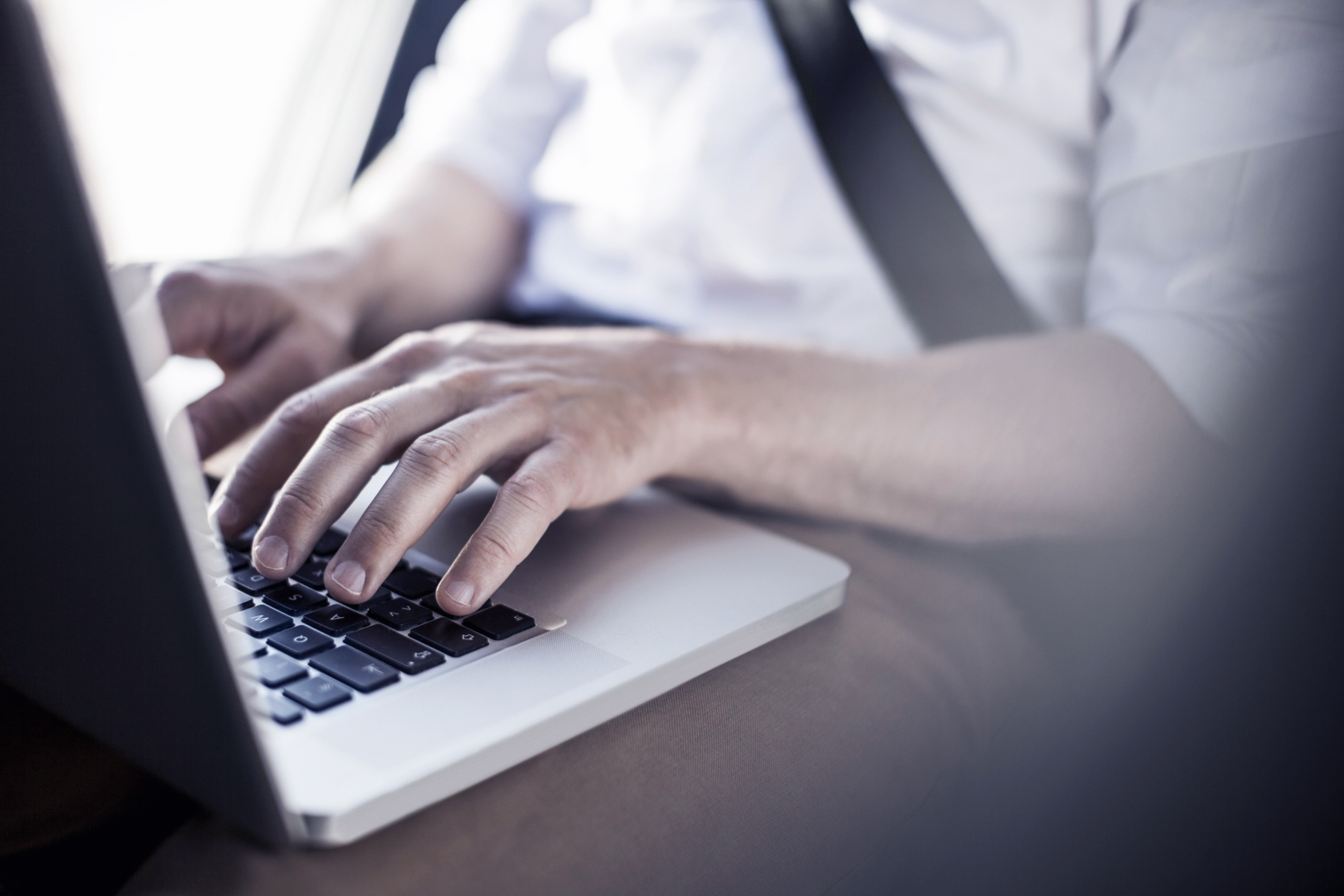 Midsection of businessman using laptop in taxi