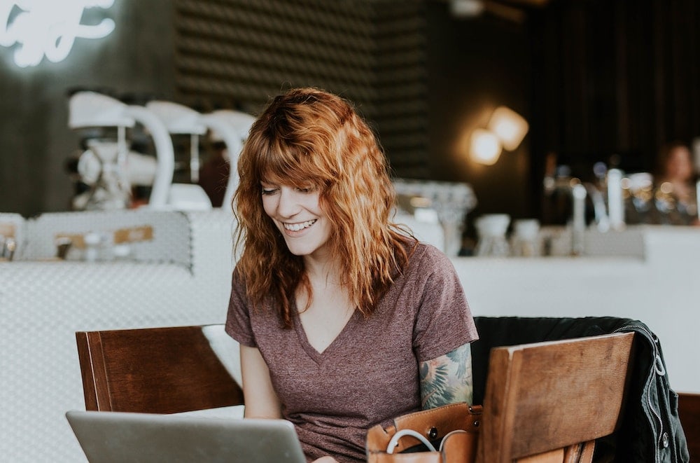 Woman using a laptop at a coffee shop and having a great time